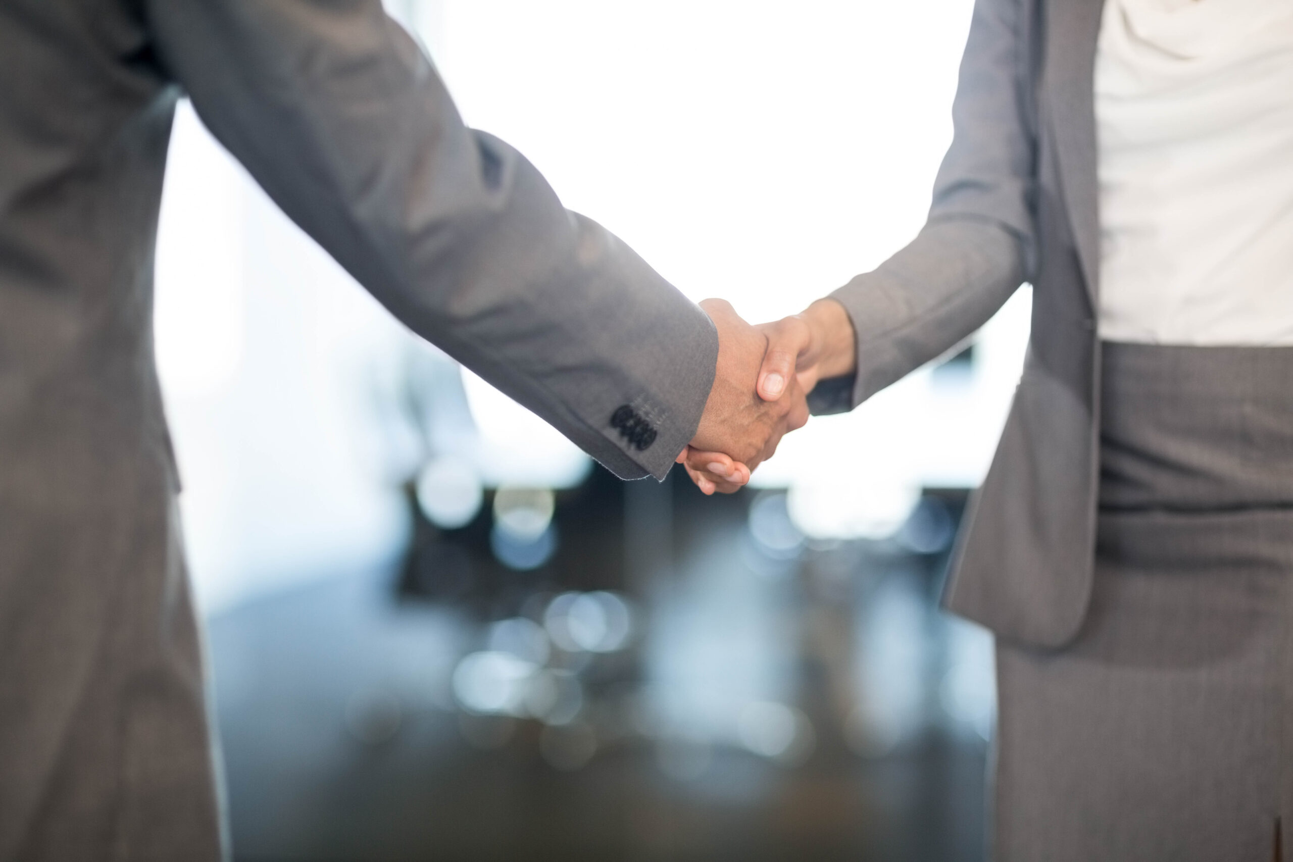 Close-up of businessman shaking hands with businesswoman in office